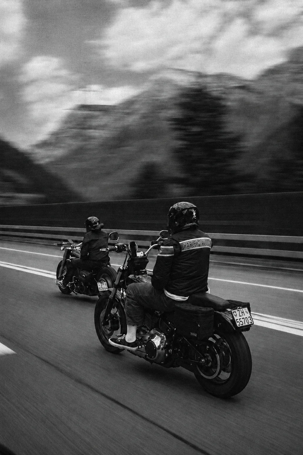 Two riders on classic motorcycles on an alpine road in Switzerland